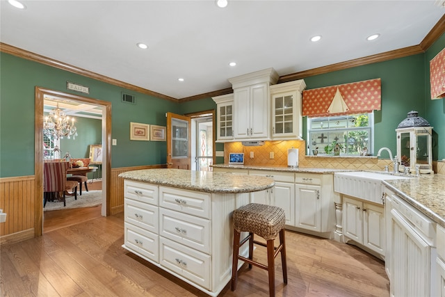 kitchen featuring dishwasher, light stone counters, crown molding, a chandelier, and light hardwood / wood-style floors