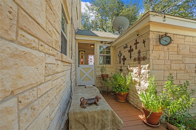 view of exterior entry with roof with shingles