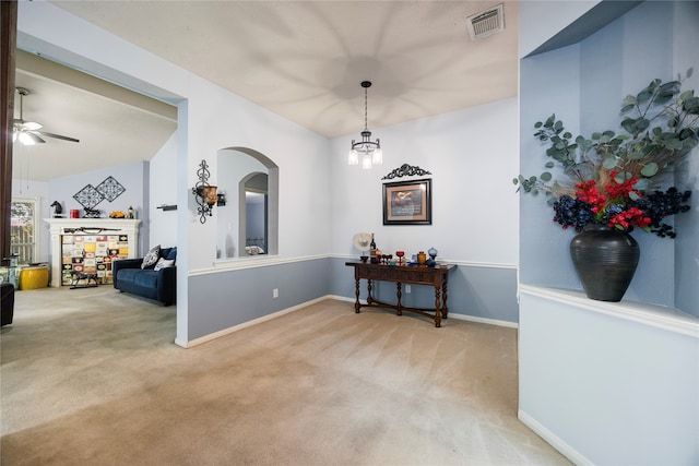 carpeted entrance foyer featuring ceiling fan with notable chandelier