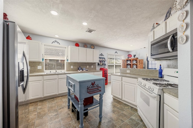 kitchen with white cabinetry, sink, appliances with stainless steel finishes, a textured ceiling, and backsplash