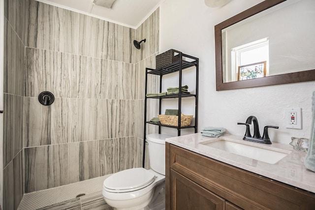 bathroom with tiled shower, vanity, and toilet