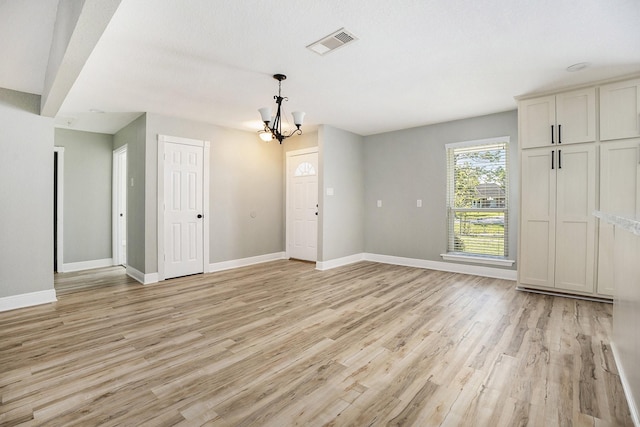 unfurnished room with light hardwood / wood-style floors and an inviting chandelier