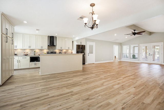 kitchen with white cabinets, light hardwood / wood-style floors, black appliances, and wall chimney range hood