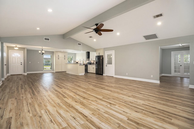 unfurnished living room with vaulted ceiling with beams, ceiling fan with notable chandelier, and light wood-type flooring