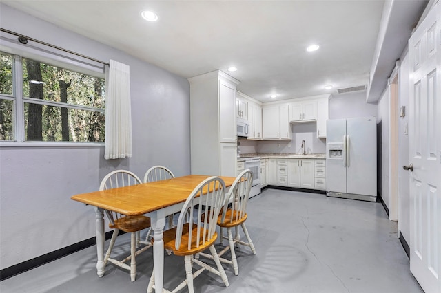 kitchen featuring white cabinetry, sink, and white appliances