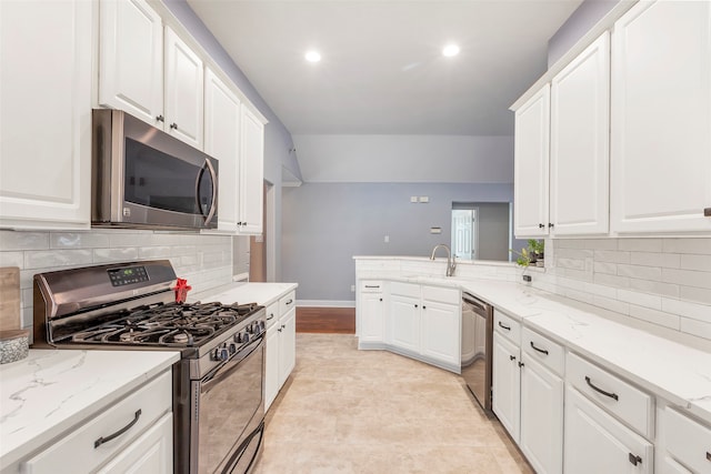 kitchen featuring decorative backsplash, sink, white cabinets, appliances with stainless steel finishes, and light stone counters