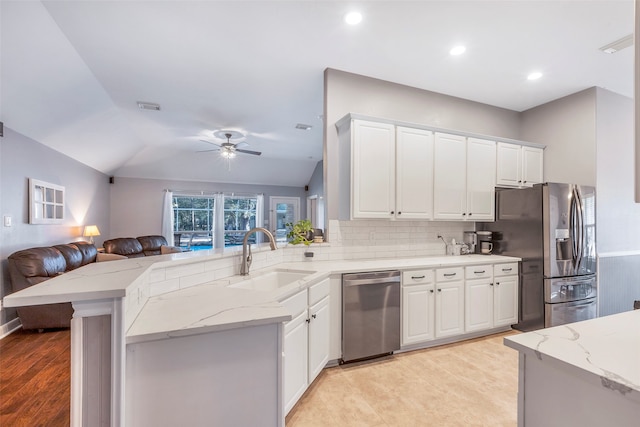 kitchen featuring white cabinetry, stainless steel appliances, vaulted ceiling, and kitchen peninsula