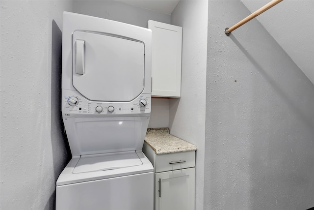 laundry room featuring stacked washing maching and dryer and cabinets