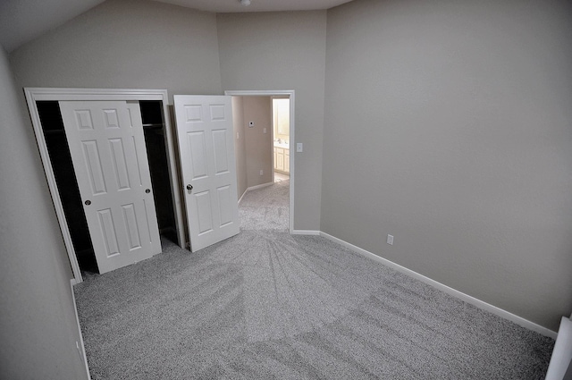 unfurnished bedroom featuring vaulted ceiling, carpet flooring, and a closet