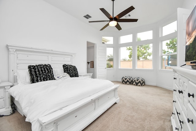 bedroom with ceiling fan, light carpet, and a towering ceiling