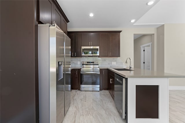 kitchen with decorative backsplash, kitchen peninsula, sink, dark brown cabinetry, and appliances with stainless steel finishes