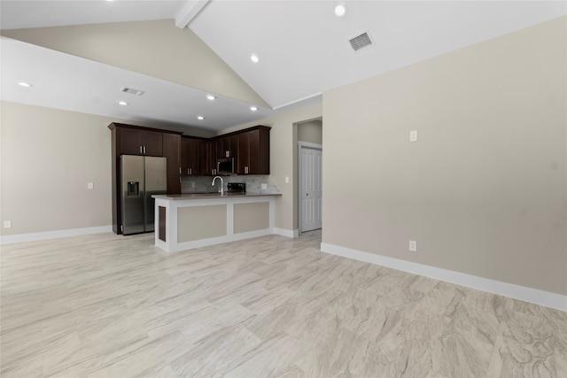 kitchen featuring beam ceiling, dark brown cabinets, a kitchen island with sink, sink, and stainless steel appliances