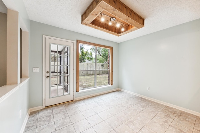 empty room with a textured ceiling and light tile patterned floors