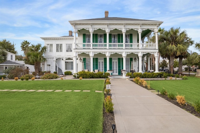 view of front of home with a balcony, a front yard, and covered porch