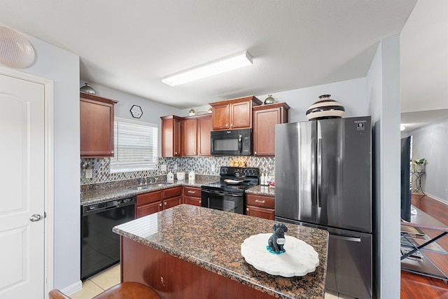 kitchen with black appliances, light hardwood / wood-style floors, a kitchen island, and dark stone counters