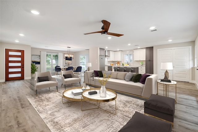 living room featuring light hardwood / wood-style flooring and ceiling fan with notable chandelier