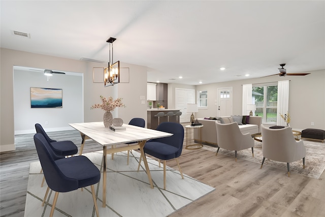 dining room featuring light hardwood / wood-style flooring and ceiling fan with notable chandelier