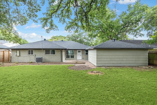 rear view of property with cooling unit and a lawn