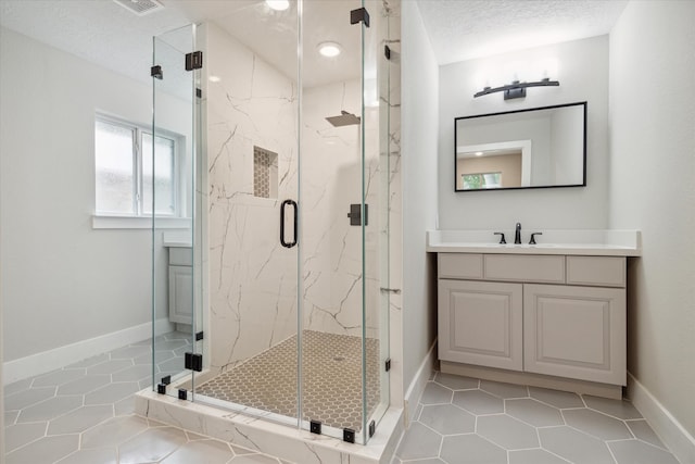 bathroom featuring vanity, a textured ceiling, tile patterned flooring, and a shower with door