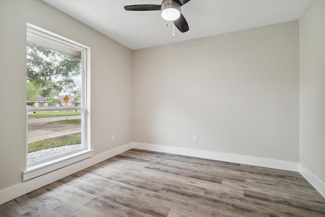 empty room with ceiling fan, light wood-type flooring, and plenty of natural light