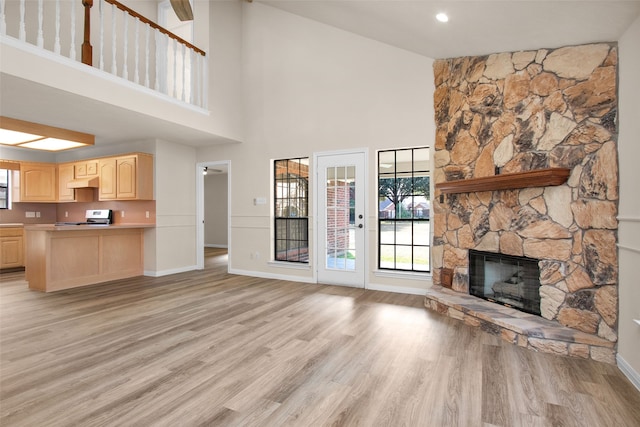 unfurnished living room with light hardwood / wood-style floors, a fireplace, and a high ceiling