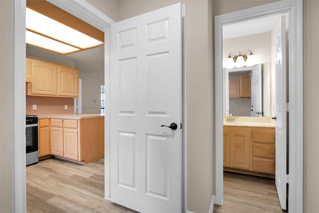 kitchen with light hardwood / wood-style flooring, light brown cabinetry, and stainless steel range