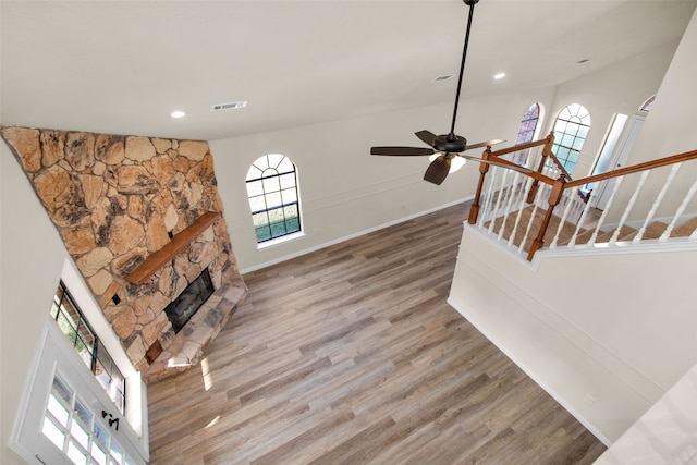 living room featuring ceiling fan, french doors, a stone fireplace, high vaulted ceiling, and hardwood / wood-style flooring