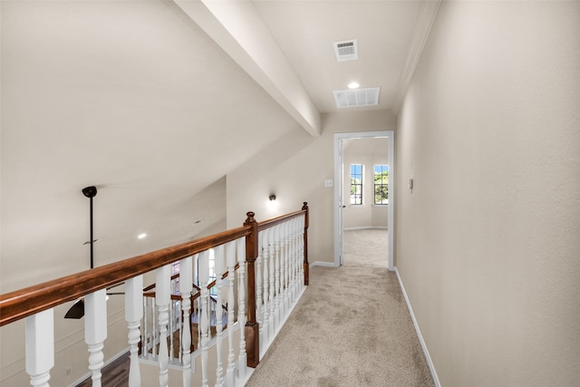 corridor featuring light carpet, beam ceiling, and ornamental molding