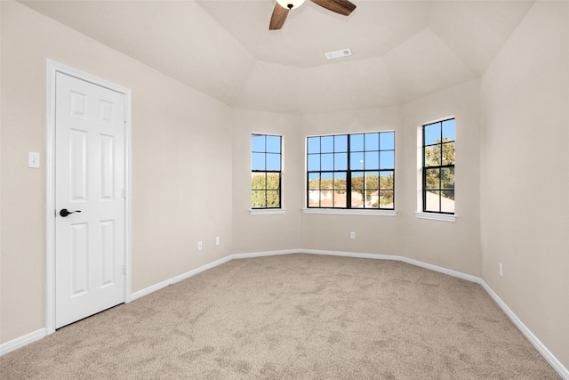 empty room featuring ceiling fan, light colored carpet, a healthy amount of sunlight, and lofted ceiling