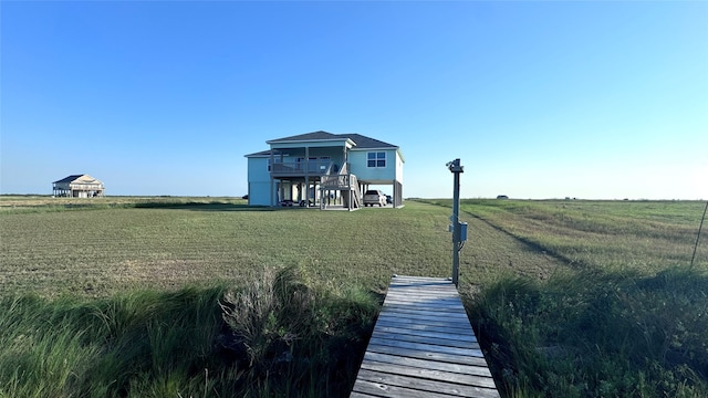 back of house with a rural view and a yard