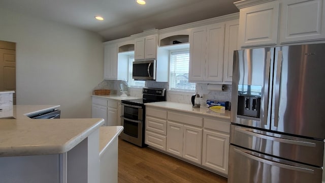 kitchen with stainless steel appliances, white cabinets, backsplash, and light wood-type flooring