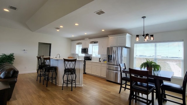 kitchen featuring stainless steel appliances, an inviting chandelier, white cabinets, light hardwood / wood-style flooring, and decorative light fixtures