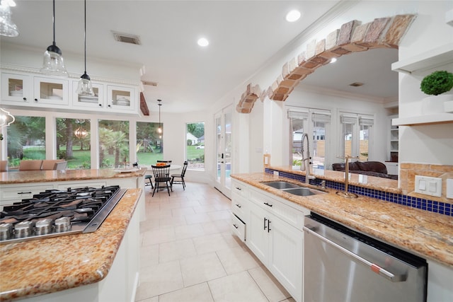 kitchen with hanging light fixtures, stainless steel appliances, sink, white cabinetry, and light stone counters