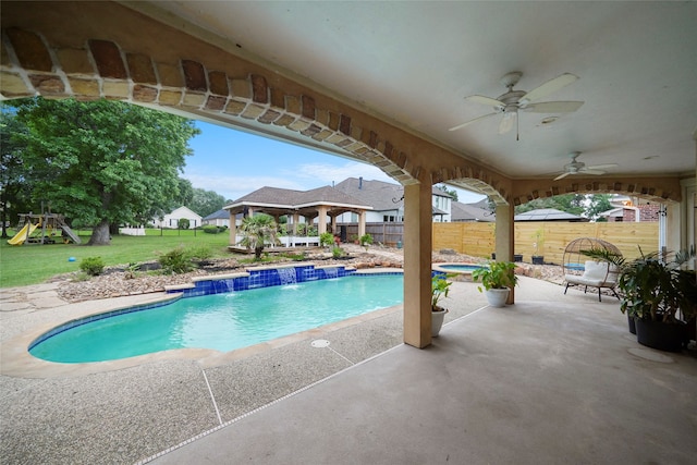 view of swimming pool with pool water feature, a patio, a playground, and ceiling fan