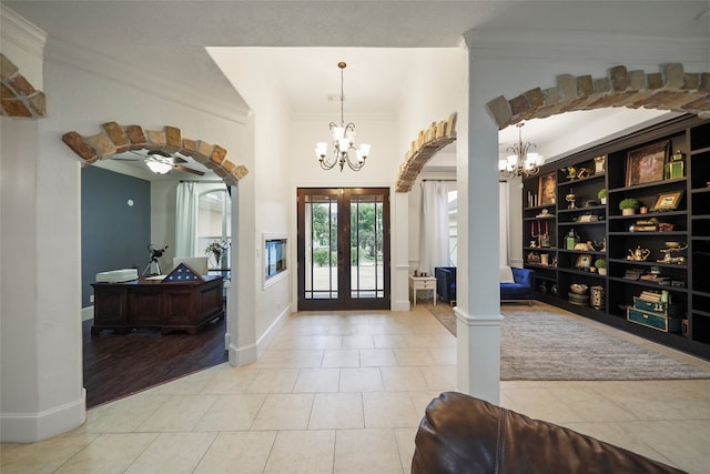 foyer entrance featuring french doors, wood-type flooring, ornamental molding, and ceiling fan with notable chandelier