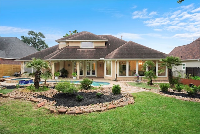 rear view of house featuring a patio, a pool with hot tub, and a lawn