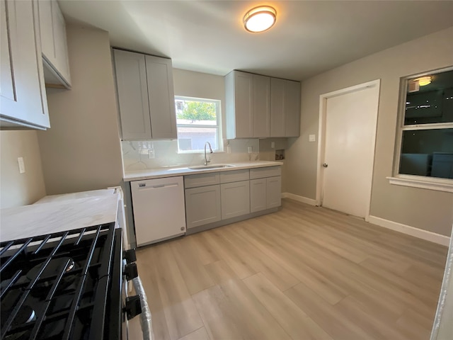 kitchen with sink, dishwasher, light hardwood / wood-style floors, decorative backsplash, and range with gas stovetop