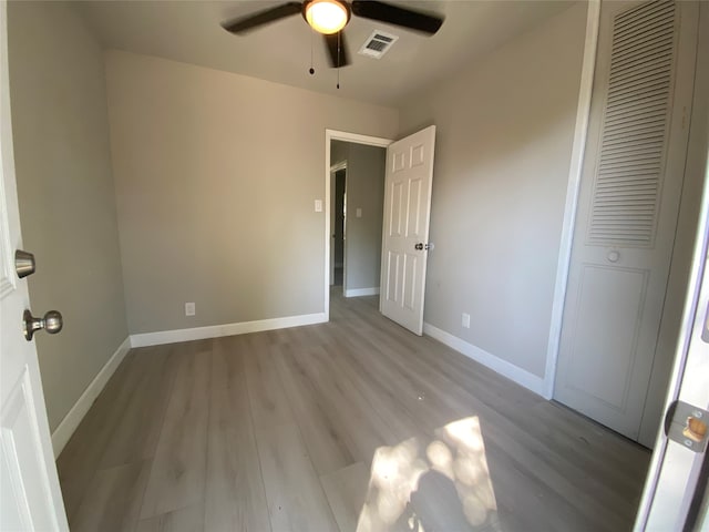 unfurnished bedroom with a closet, light hardwood / wood-style floors, and ceiling fan