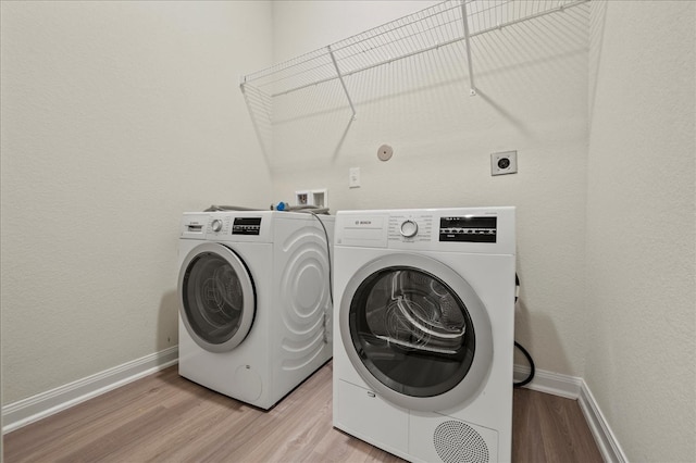 laundry area with separate washer and dryer and light wood-type flooring