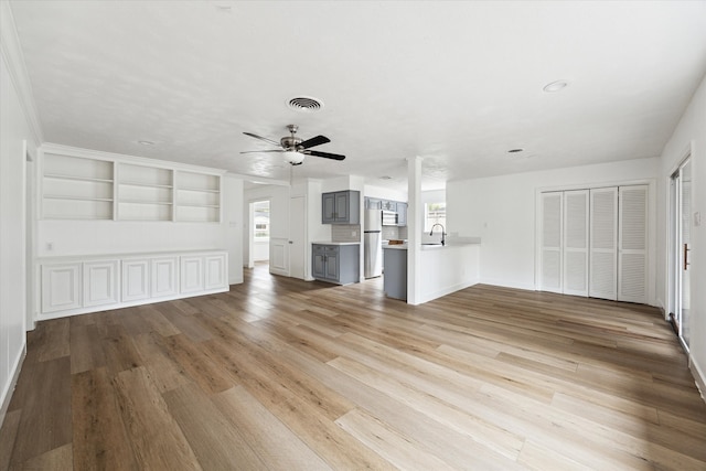 unfurnished living room featuring a wealth of natural light, sink, light hardwood / wood-style flooring, and built in features