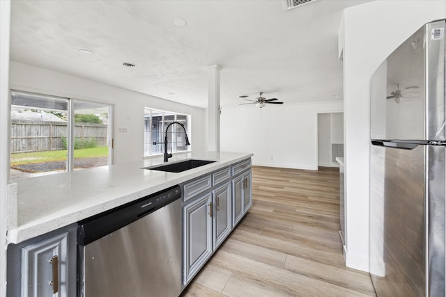 kitchen with gray cabinetry, stainless steel appliances, sink, light hardwood / wood-style floors, and ceiling fan