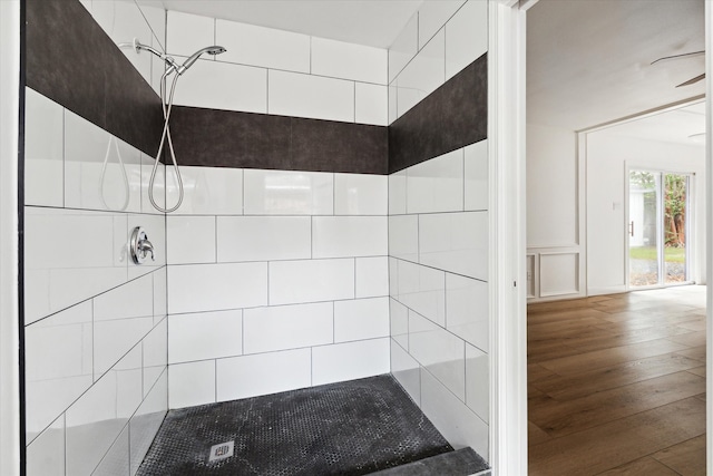 bathroom with a tile shower and wood-type flooring