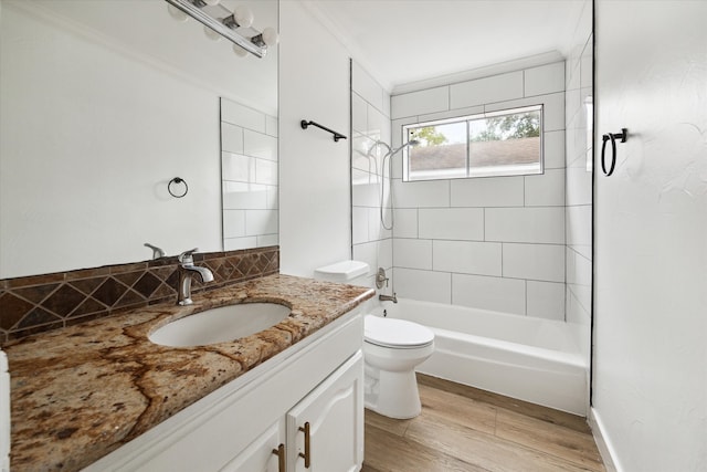 full bathroom featuring tiled shower / bath, vanity, hardwood / wood-style floors, and toilet