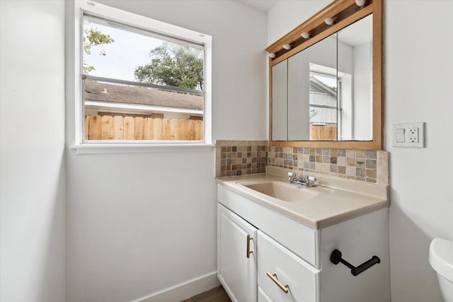 bathroom with vanity, toilet, and tasteful backsplash