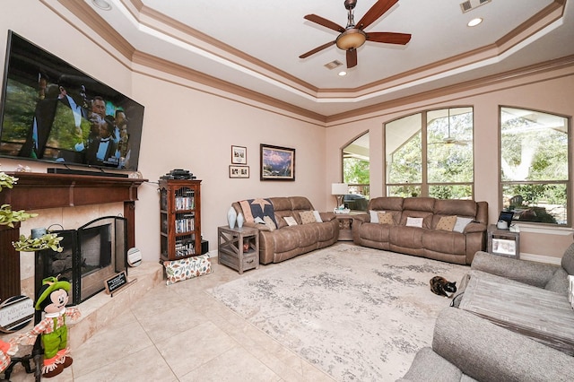 tiled living room featuring ceiling fan, ornamental molding, a premium fireplace, and a tray ceiling