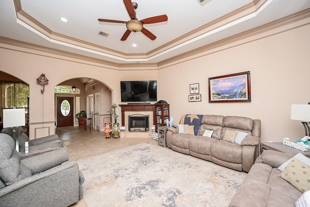 tiled living room with a tray ceiling, ceiling fan, and ornamental molding