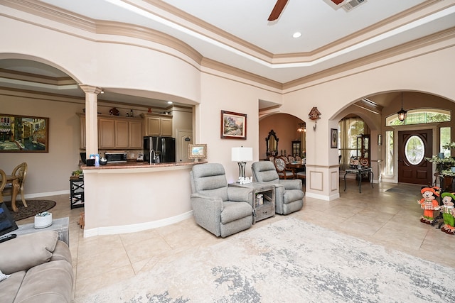 tiled living room with ornate columns, ceiling fan, and ornamental molding