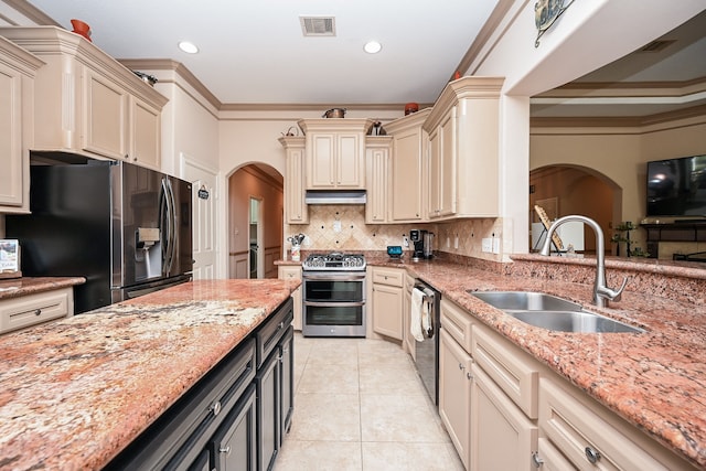 kitchen with sink, crown molding, cream cabinetry, light stone counters, and stainless steel appliances