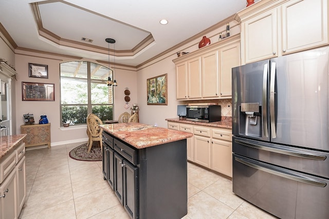 kitchen with cream cabinetry, appliances with stainless steel finishes, a center island, and light stone counters