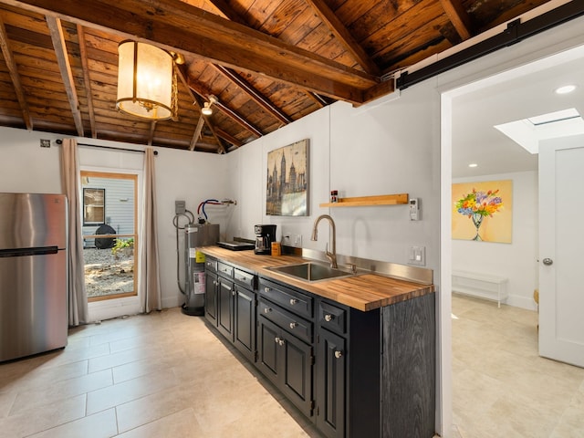 kitchen featuring sink, wood ceiling, wood counters, water heater, and stainless steel refrigerator